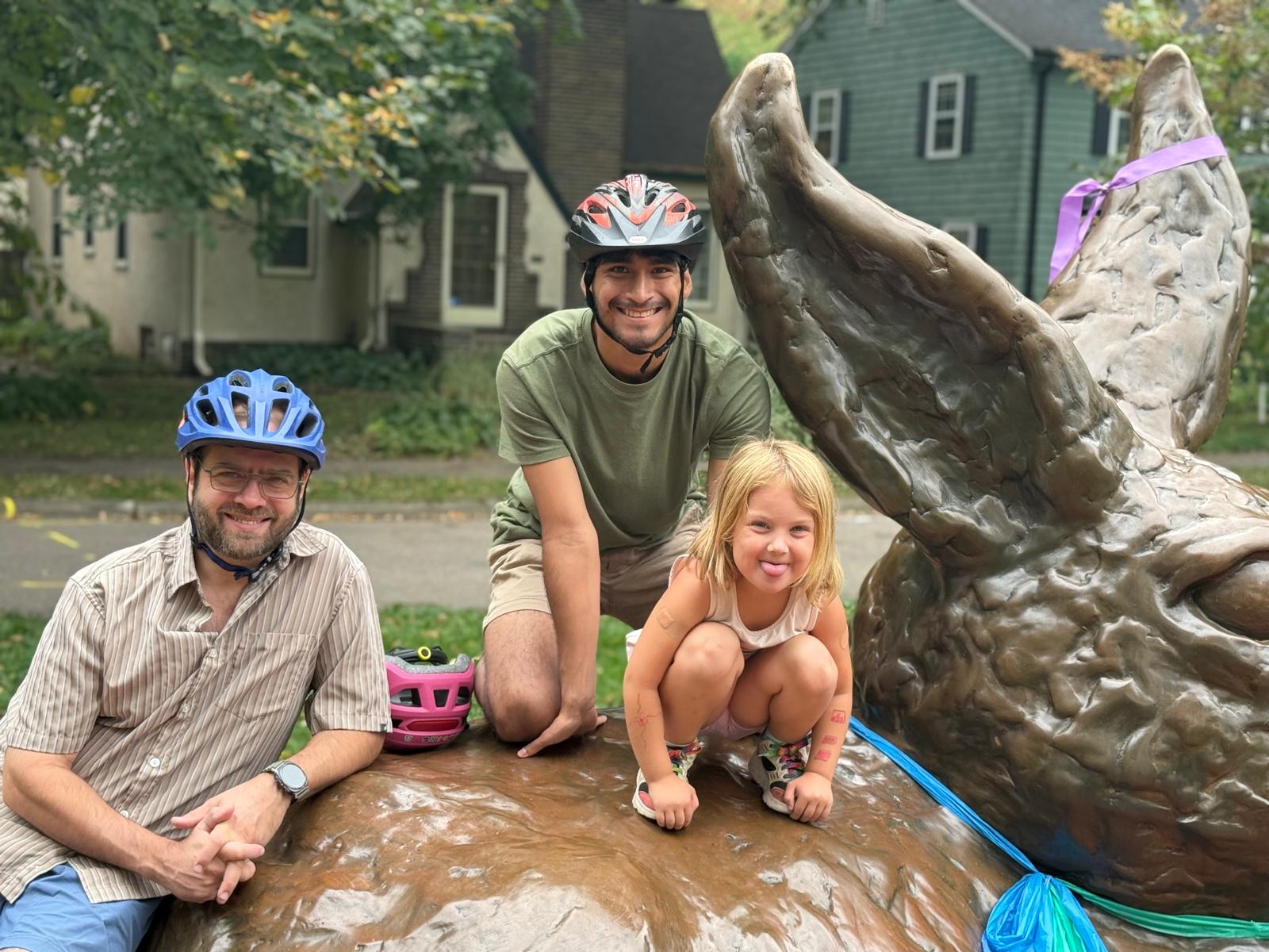Family biking by wolf statue